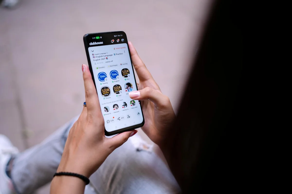 Close-up of a woman using a smartphone with social media app open. Hands holding