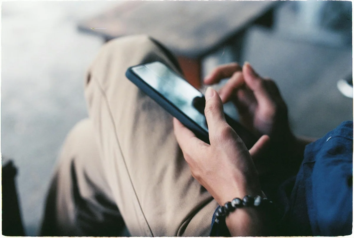 A close-up view of a person using a smartphone indoors, showcasing modern techno