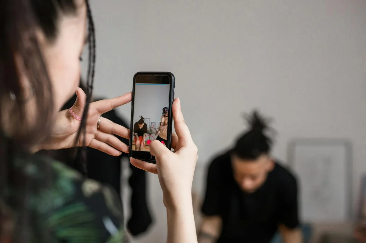 Close-up of a person recording a video with a smartphone indoors, focusing on cr