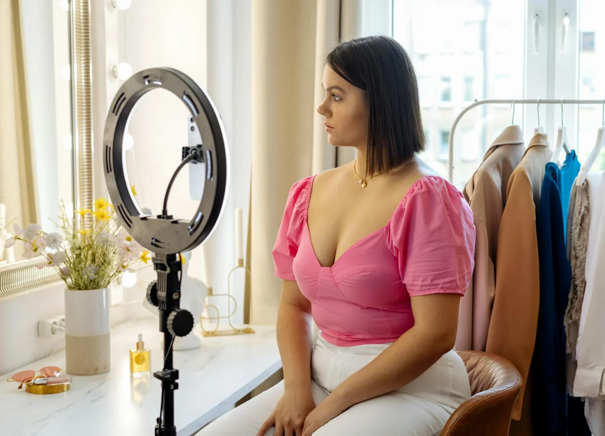 Perfil de TikTok optimizado: la base de tu éxito en 2026 — Young woman in pink top setting up camera for video recording with ring light in