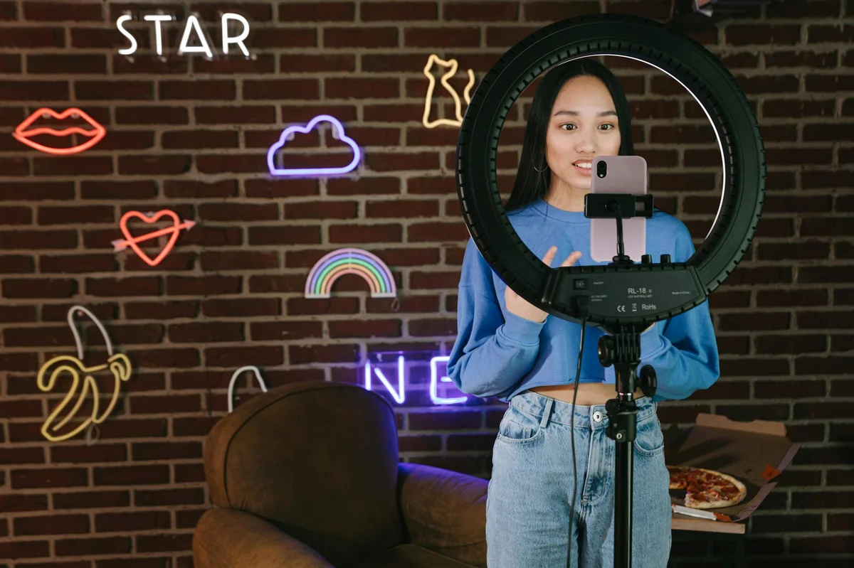 Guiones naturales en TikTok: cómo estructurar tu video sin p... — Young woman filming vlog with smartphone and ring light in stylish room with neo