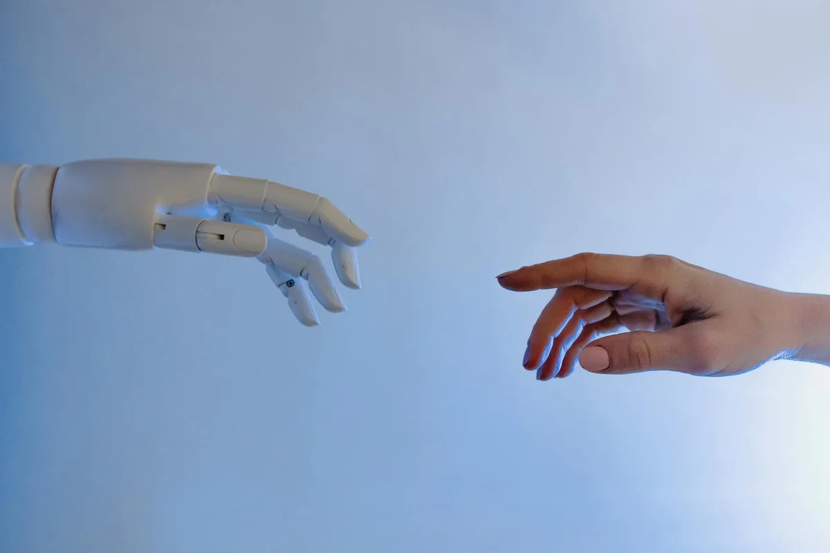 Claude vs ChatGPT: por qué Claude no es solo otro chatbot, e... — A human hand reaching towards a robotic hand symbolizing technology and connecti
