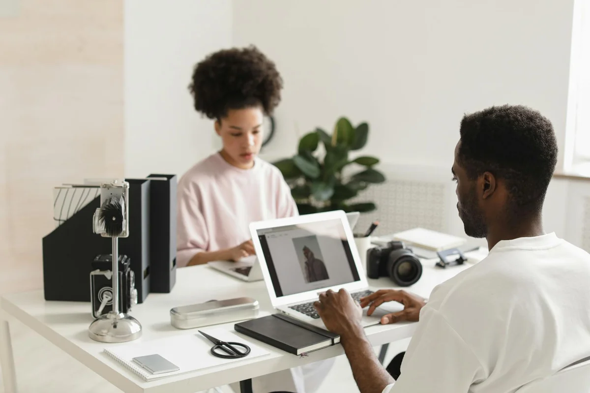 Qué es TikTok en 2026: más allá de una app de videos cortos — Two creative professionals collaborating in a bright, modern office setting with