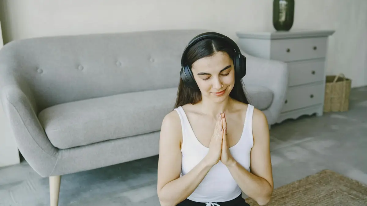 Young woman enjoying meditation with headphones at home, eyes closed, in a peaceful living room sett