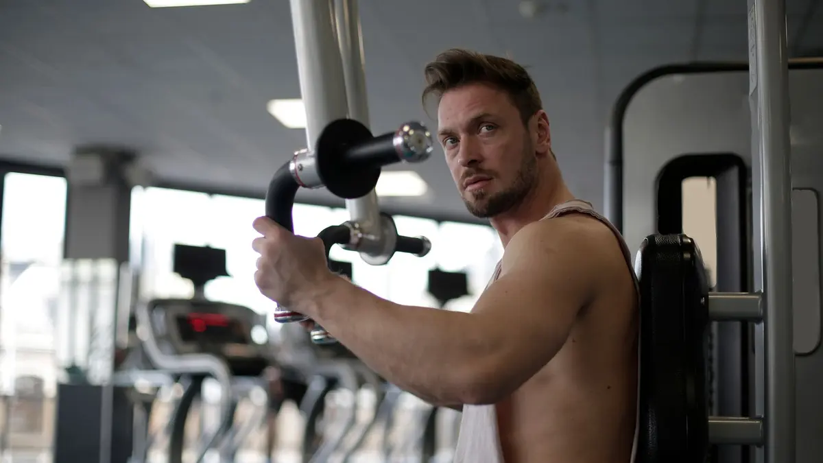 Focused man working out in a gym, showcasing biceps and determination.