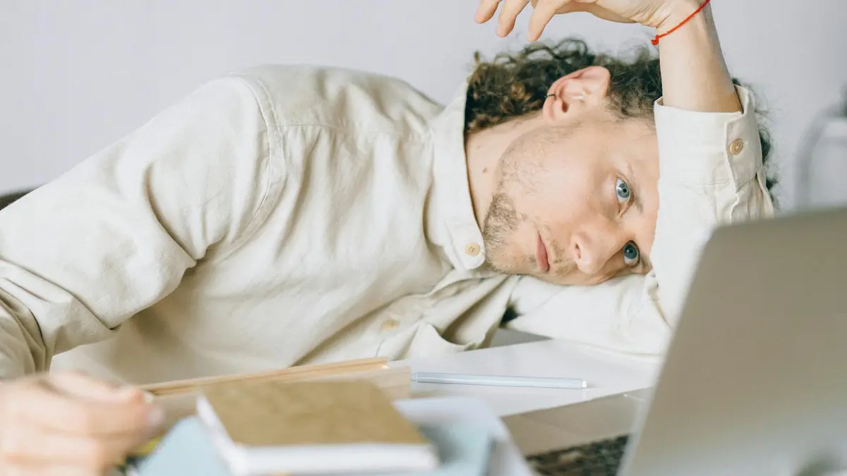 A tired Caucasian man at a desk, showing signs of exhaustion and stress, exemplifying workplace burn