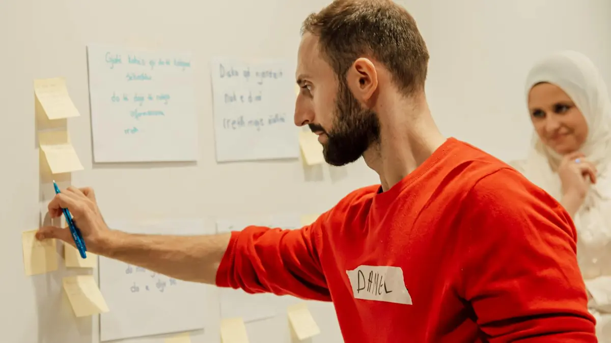 Man and woman collaborating with sticky notes on a wall during a creative session.